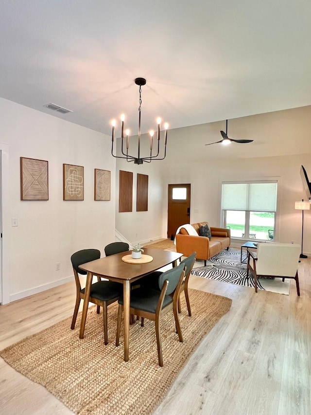 dining room with light wood-type flooring, baseboards, visible vents, and ceiling fan with notable chandelier