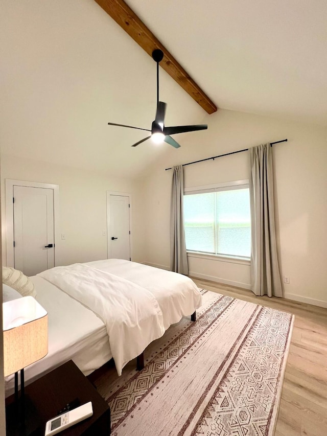 bedroom with light wood-type flooring, ceiling fan, lofted ceiling with beams, and baseboards