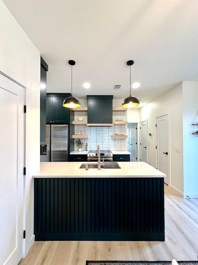 kitchen featuring a sink, visible vents, light countertops, stainless steel refrigerator with ice dispenser, and open shelves