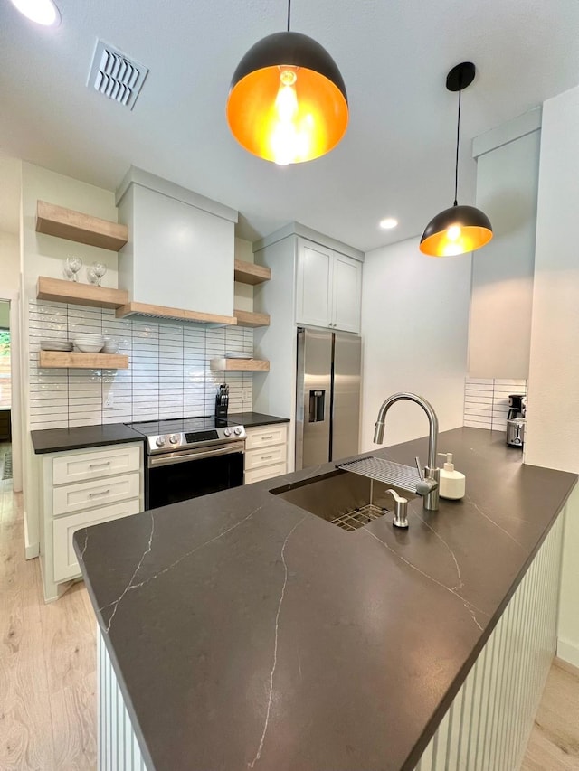 kitchen featuring open shelves, visible vents, appliances with stainless steel finishes, a sink, and a peninsula