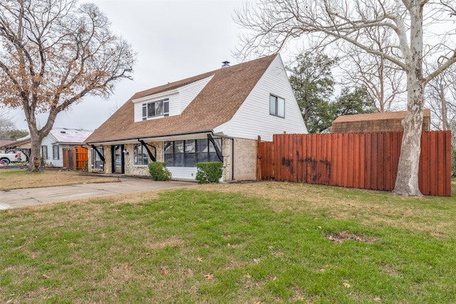 view of front of property with brick siding, fence, concrete driveway, and a front yard