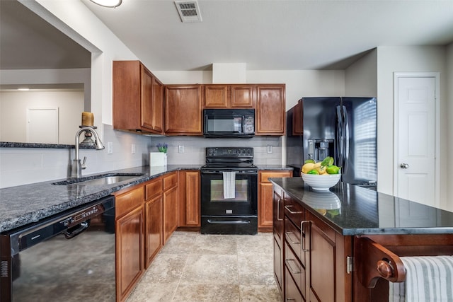 kitchen featuring dark stone counters, black appliances, a sink, and visible vents