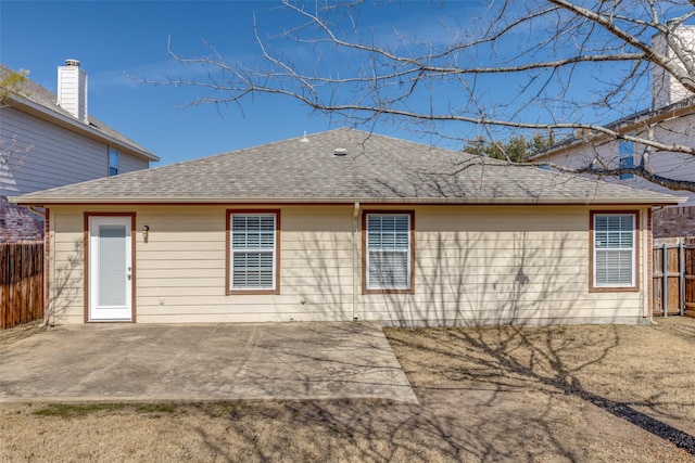 back of property with a patio area, fence, and roof with shingles