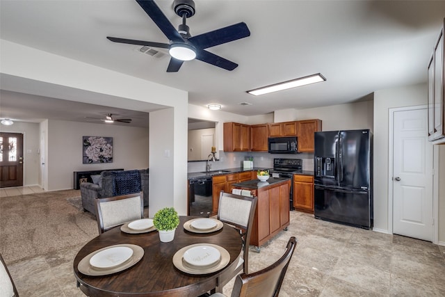 kitchen with brown cabinets, dark countertops, visible vents, a sink, and black appliances