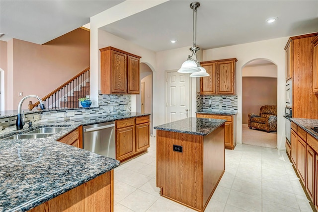 kitchen with arched walkways, a kitchen island, oven, stainless steel dishwasher, and a sink