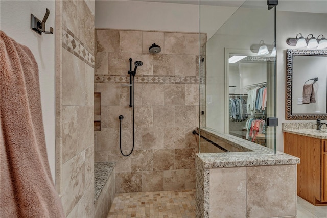 bathroom with a spacious closet, vanity, and walk in shower