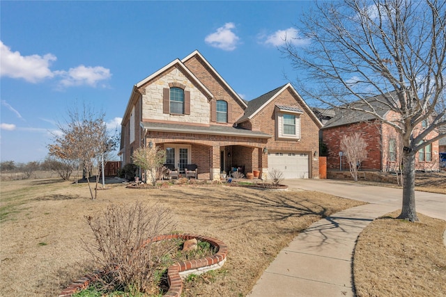 traditional-style home featuring brick siding, a porch, a garage, stone siding, and driveway