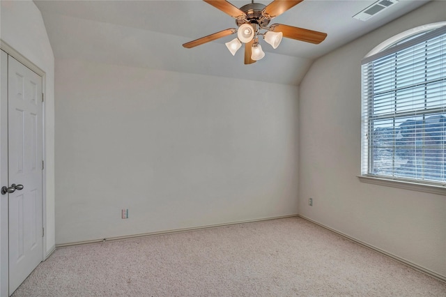 carpeted spare room featuring a ceiling fan, visible vents, and vaulted ceiling