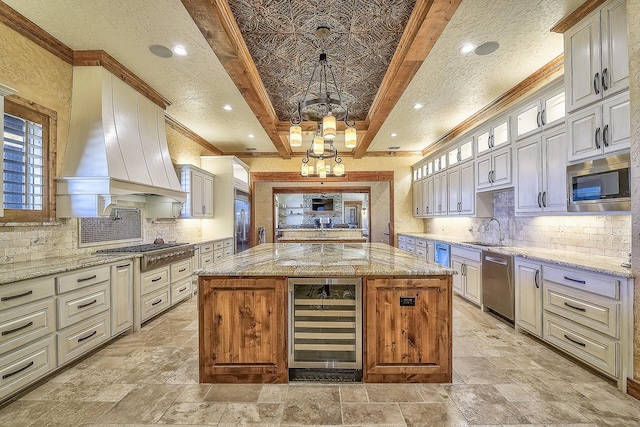 kitchen featuring wine cooler, a center island, custom exhaust hood, appliances with stainless steel finishes, and a sink