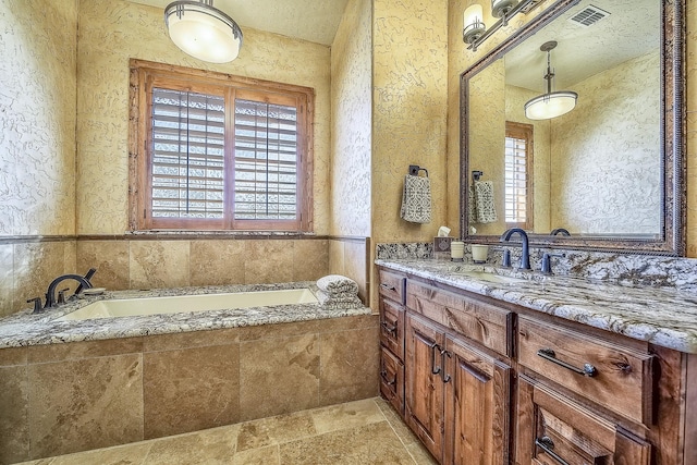 full bathroom featuring visible vents, a bath, and vanity