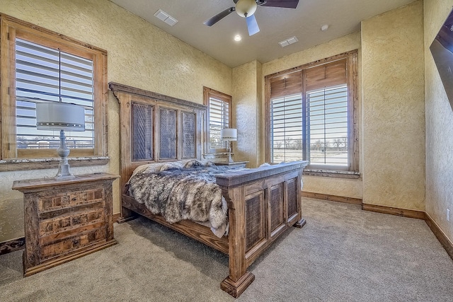 carpeted bedroom featuring baseboards, visible vents, and a textured wall