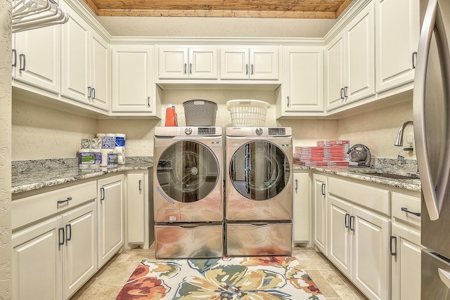 washroom with cabinet space, a sink, and independent washer and dryer