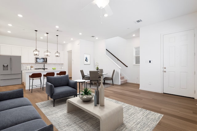 living room featuring light wood finished floors, stairway, visible vents, and recessed lighting