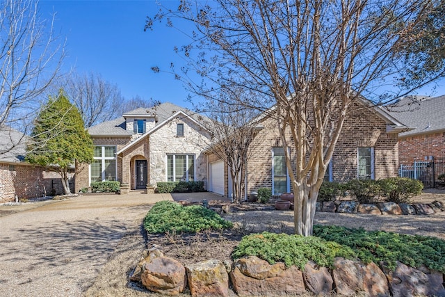 view of front facade with a garage, brick siding, concrete driveway, and fence