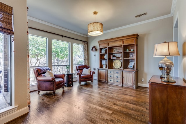 living area with baseboards, crown molding, visible vents, and wood finished floors