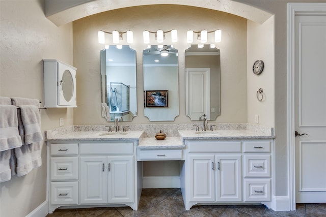 full bath featuring baseboards, double vanity, a sink, and crown molding