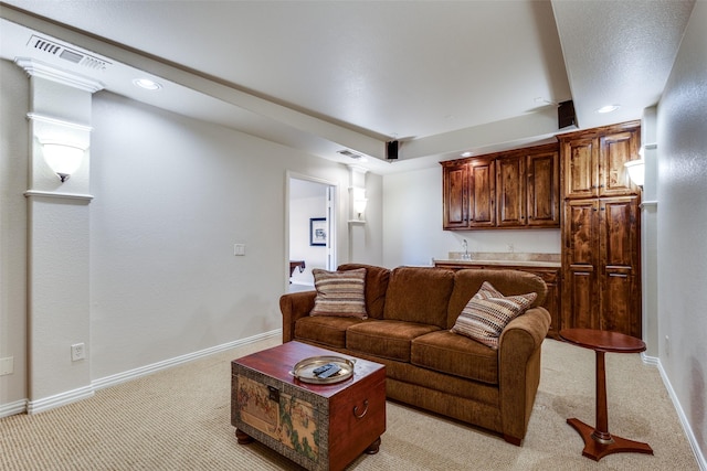 living area with light colored carpet, visible vents, decorative columns, and baseboards