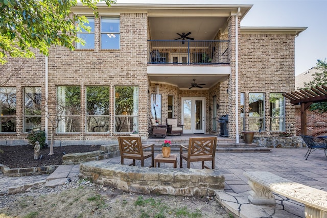 back of house featuring brick siding, ceiling fan, a balcony, and a patio