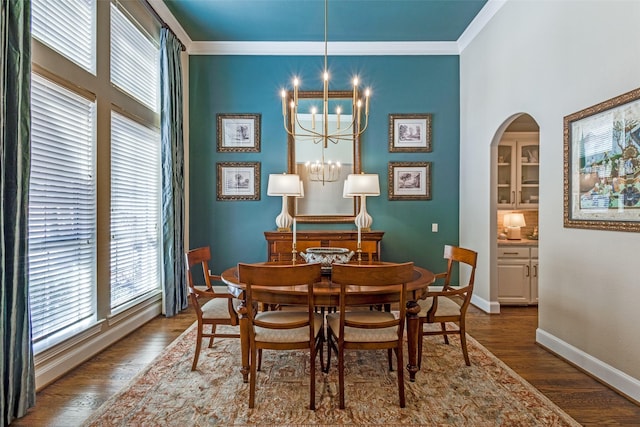 dining room featuring arched walkways, dark wood-type flooring, crown molding, and an inviting chandelier