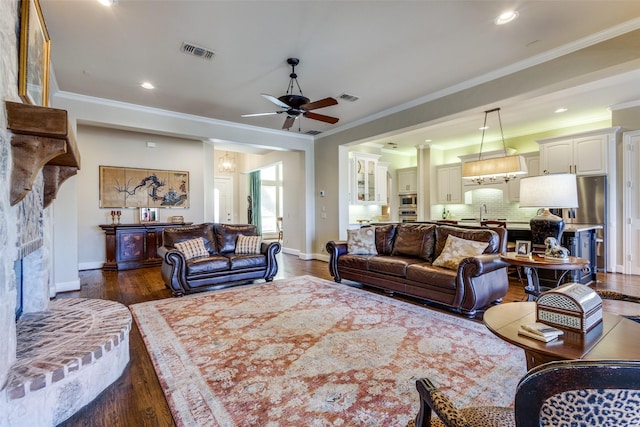 living room featuring dark wood-type flooring, a large fireplace, visible vents, and baseboards