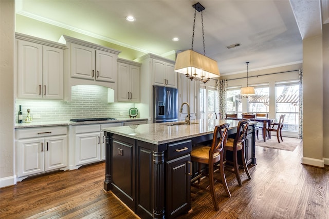 1313 Stoneoak Dr, Mckinney, TX 75072 - kitchen featuring refrigerator with ice dispenser, a sink, gas cooktop, crown molding, and an island with sink
