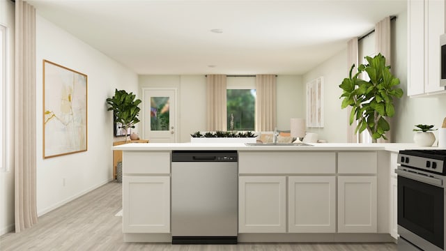 kitchen with light wood-style flooring, a peninsula, stainless steel appliances, light countertops, and a sink