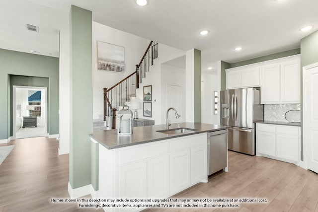 kitchen with stainless steel appliances, light wood-style floors, white cabinets, and a sink