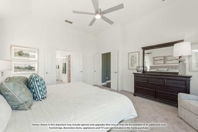 bedroom with ensuite bathroom, light colored carpet, a towering ceiling, baseboards, and visible vents