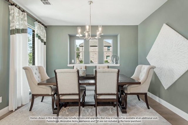 dining room featuring a chandelier, wood finished floors, visible vents, and baseboards