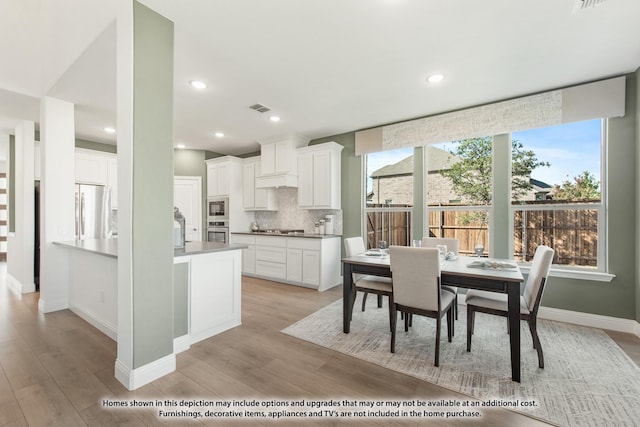 kitchen featuring stainless steel appliances, visible vents, white cabinets, light wood-style floors, and backsplash