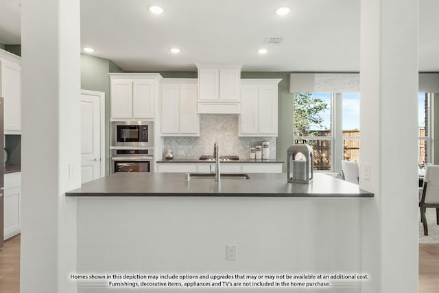 kitchen featuring dark countertops, visible vents, a sink, built in microwave, and oven