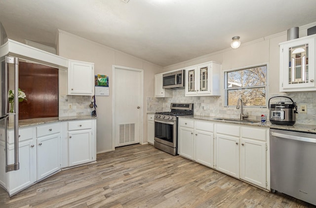 kitchen featuring stainless steel appliances, a sink, visible vents, white cabinets, and light wood finished floors