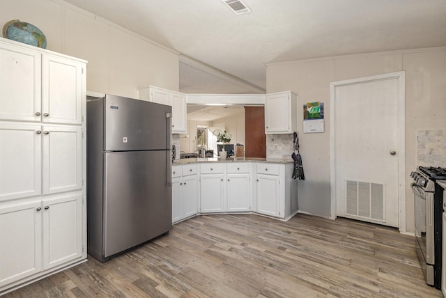 kitchen featuring lofted ceiling, stainless steel appliances, visible vents, and white cabinets