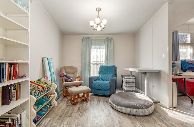 living area featuring crown molding, an inviting chandelier, and wood finished floors