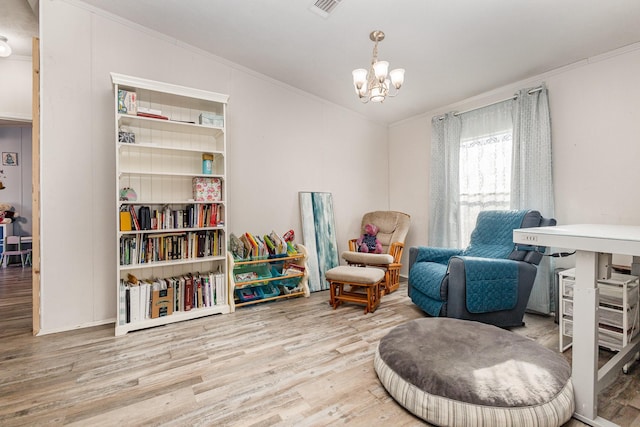 living area featuring ornamental molding, wood finished floors, visible vents, and an inviting chandelier