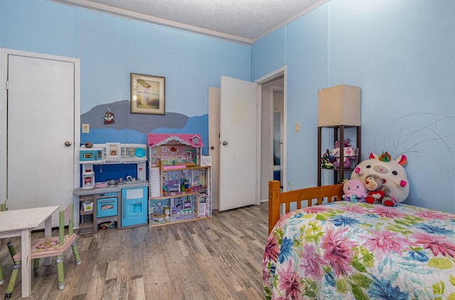 bedroom featuring crown molding, a textured ceiling, and wood finished floors