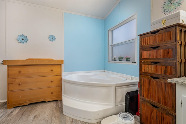 full bath with ornamental molding, a bath, and wood finished floors