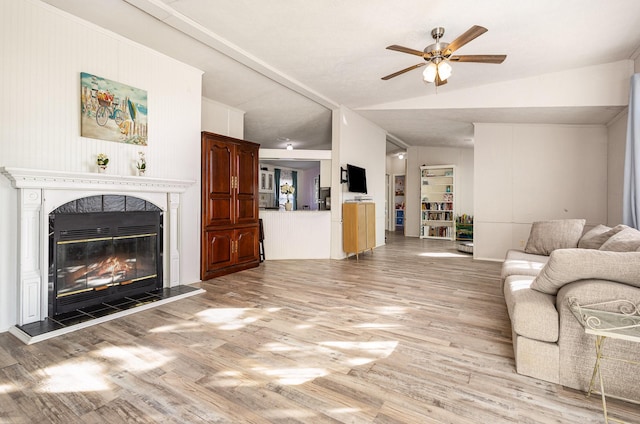 living area with vaulted ceiling, a premium fireplace, light wood-type flooring, and a ceiling fan