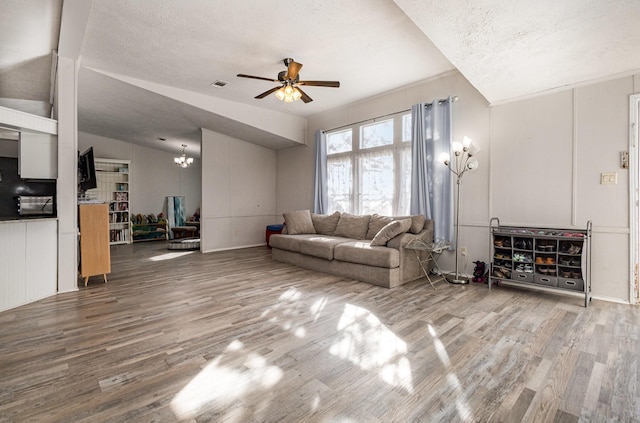 living area with a textured ceiling, ceiling fan with notable chandelier, wood finished floors, and visible vents