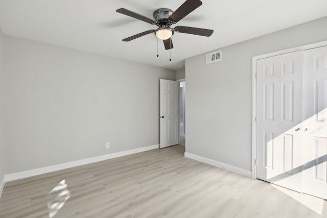 unfurnished bedroom featuring baseboards, visible vents, ceiling fan, wood finished floors, and a closet