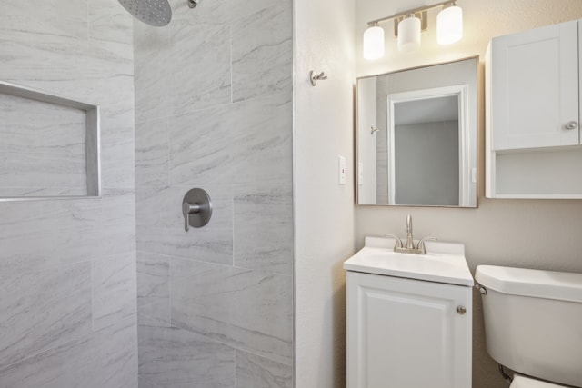 full bath featuring tiled shower, vanity, and toilet