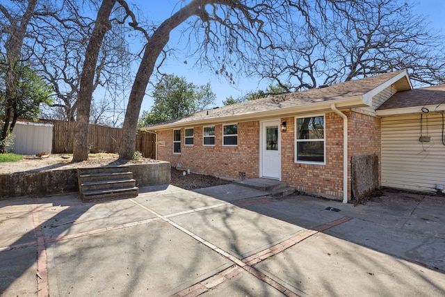 view of front of house with brick siding, a patio area, and fence