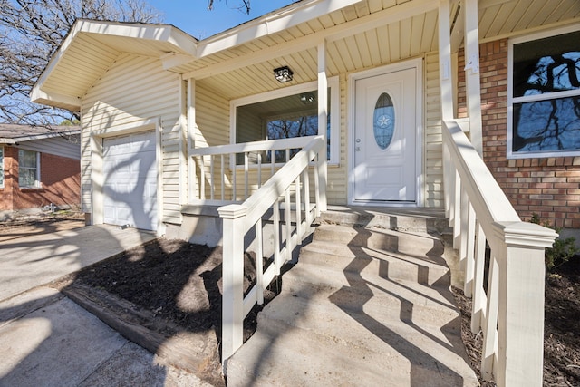 entrance to property featuring driveway, covered porch, a garage, and brick siding