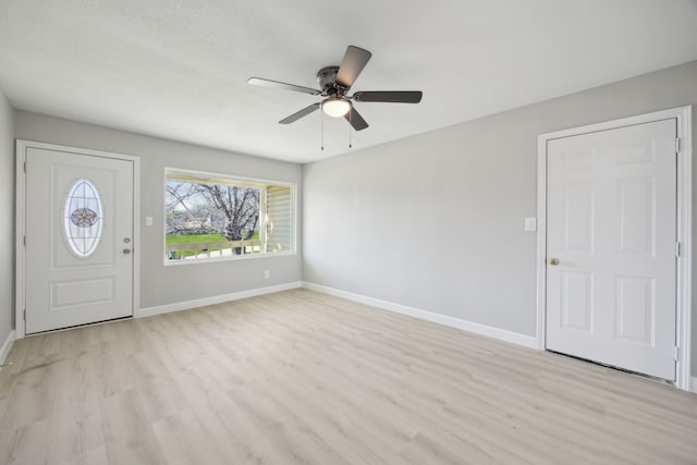 foyer entrance with light wood-type flooring, ceiling fan, and baseboards