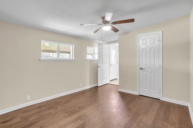 spare room with ceiling fan, baseboards, and dark wood-style flooring