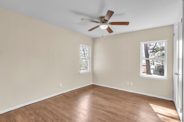 empty room with ceiling fan, wood finished floors, and baseboards