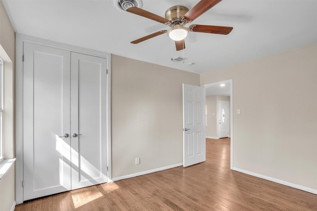 unfurnished bedroom featuring baseboards, a closet, visible vents, and wood finished floors