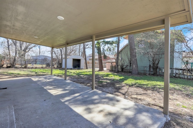 view of patio featuring an outbuilding, a storage unit, and fence