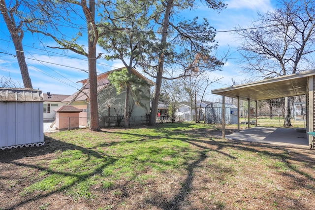 view of yard featuring a carport, an outbuilding, fence, and a storage shed