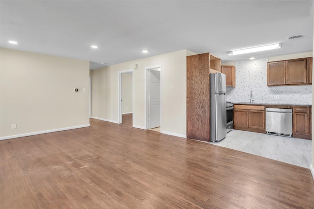 kitchen featuring open floor plan, appliances with stainless steel finishes, light wood-type flooring, and a sink